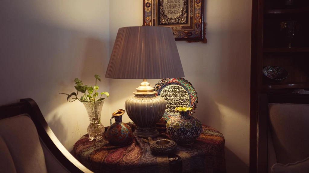 A ceramic lamp and folded throw on a side table