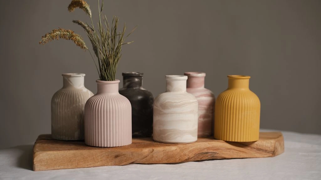 Ceramic vase with dried pampas, design books, and brass lamp on travertine